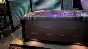 Un jacuzzi con tapa, rodeado por un patio con mantillo y plantas en macetas.