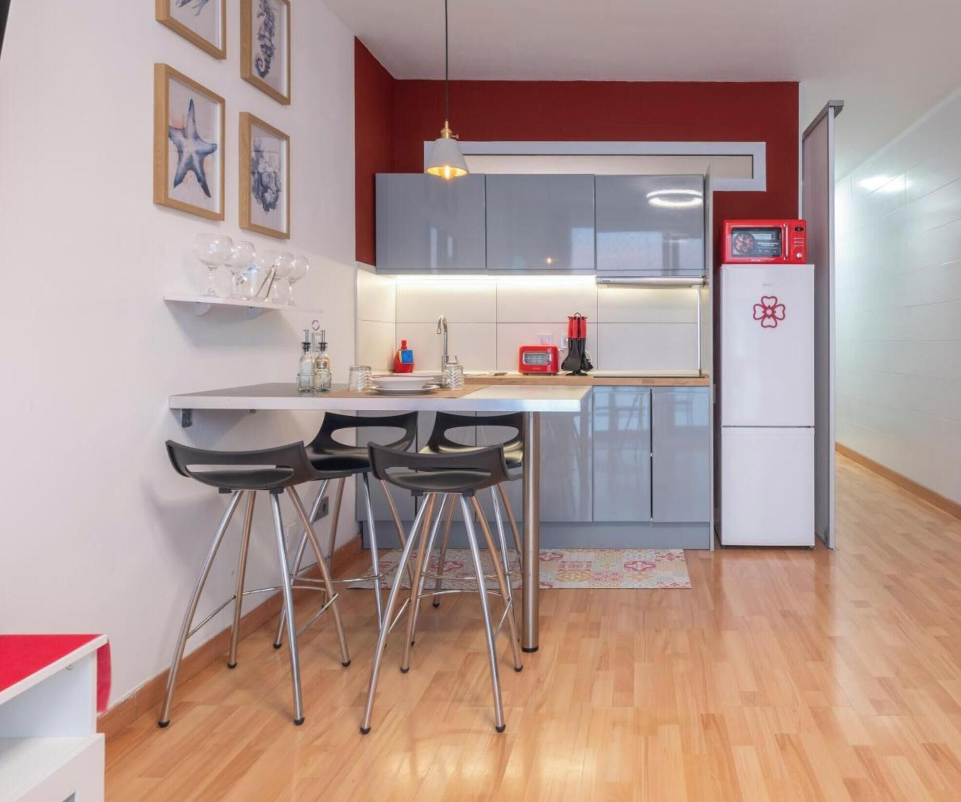 Uma cozinha compacta com área de refeições, equipada com geladeira, micro-ondas e pia.