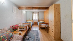 Une pièce confortable avec un canapé, deux lits en bois, une petite table avec une lampe et un tapis.