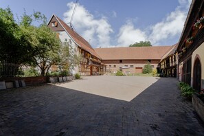 Ein Innenhof mit traditionellen Fachwerkhäusern, einem gepflasterten Weg und blauem Himmel.