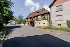 A street with a traditional half-timbered building, a clear road, and a tree-lined sidewalk.