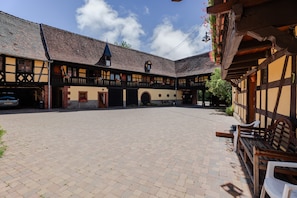 Une cour intérieure avec un bâtiment doté d’une façade traditionnelle à pans de bois, d’une tour horloge et d’une galerie couverte.
