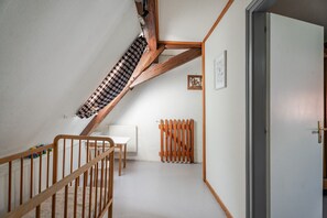 Ein Zimmer mit schrägen Wänden, einer Holztreppe, einem weißen Heizkörper und einer Tür.
