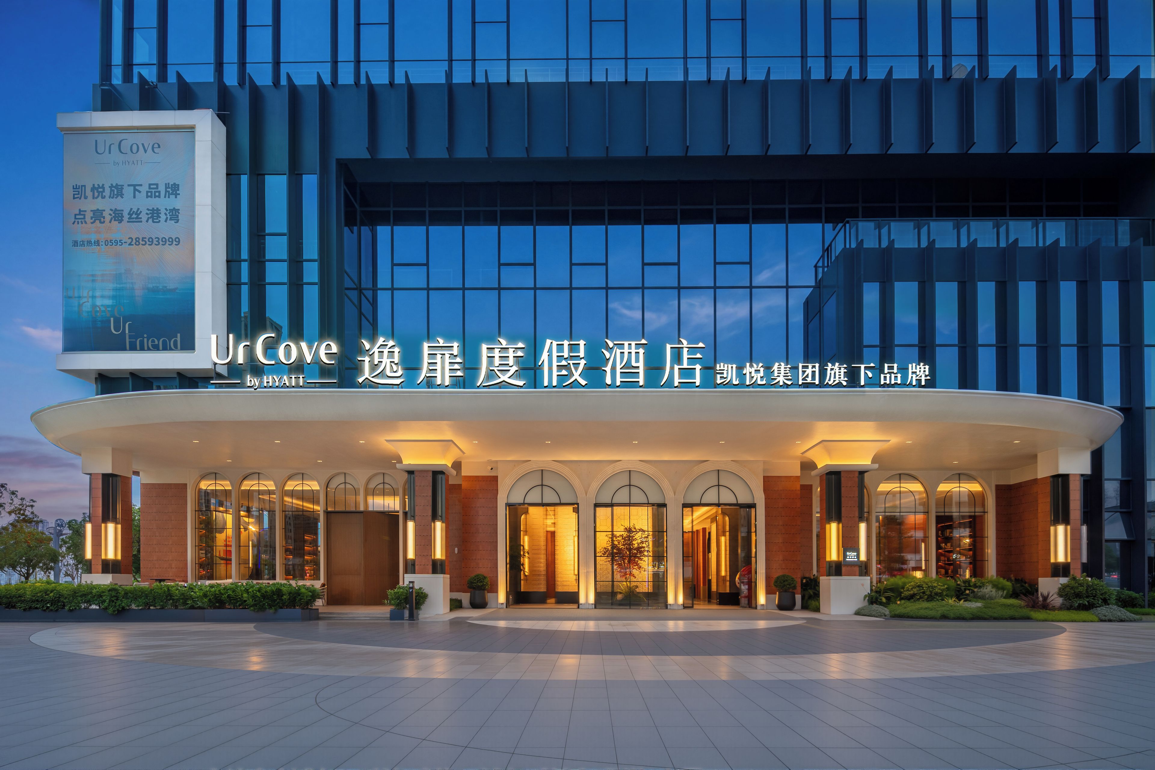 A modern hotel entrance with a curved facade, large windows, and a well-lit entrance area.