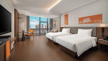 A hotel room with two beds, a TV, a balcony with a city view, and a large window.
