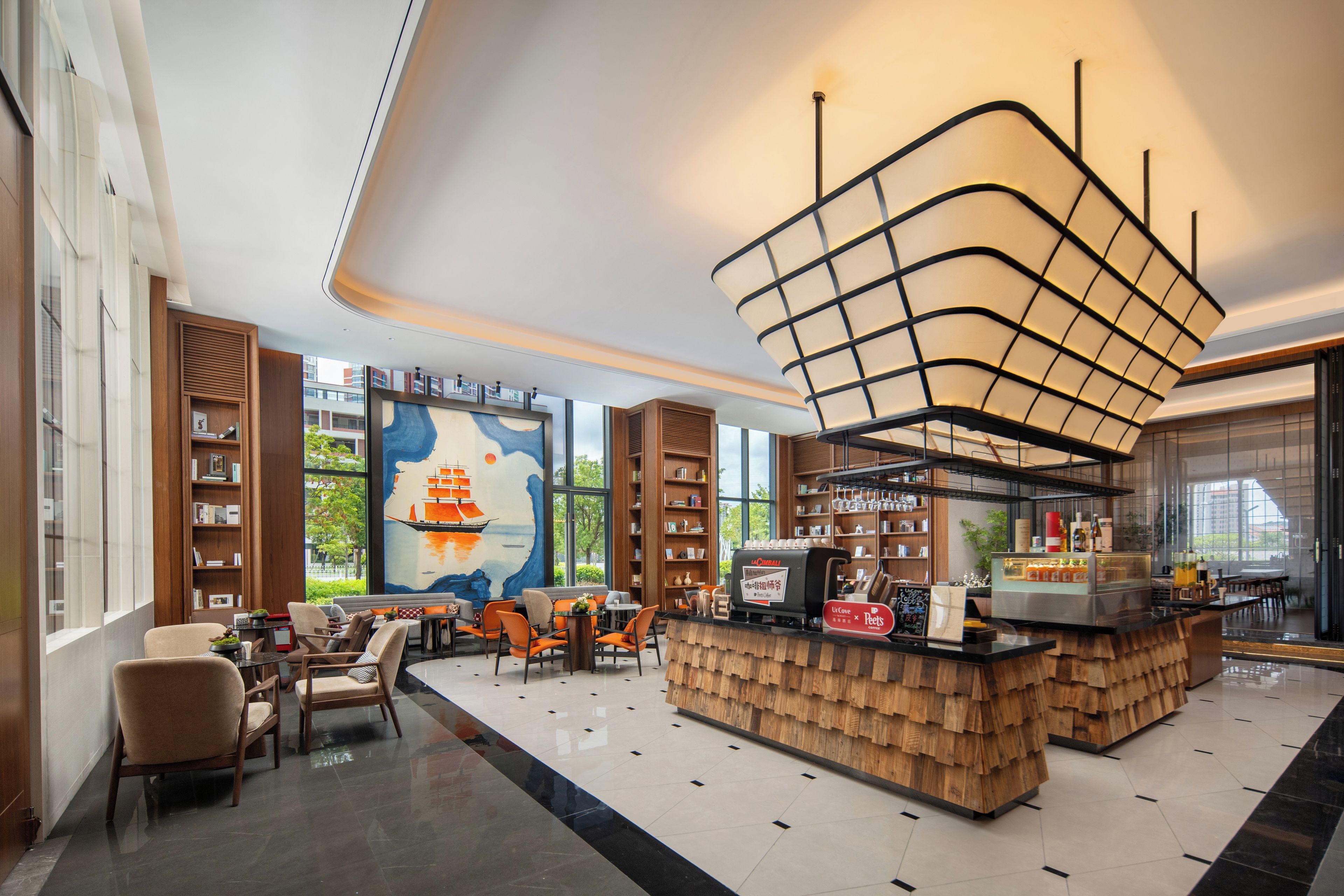 A modern interior with a central coffee bar, seating area, and a large mural.