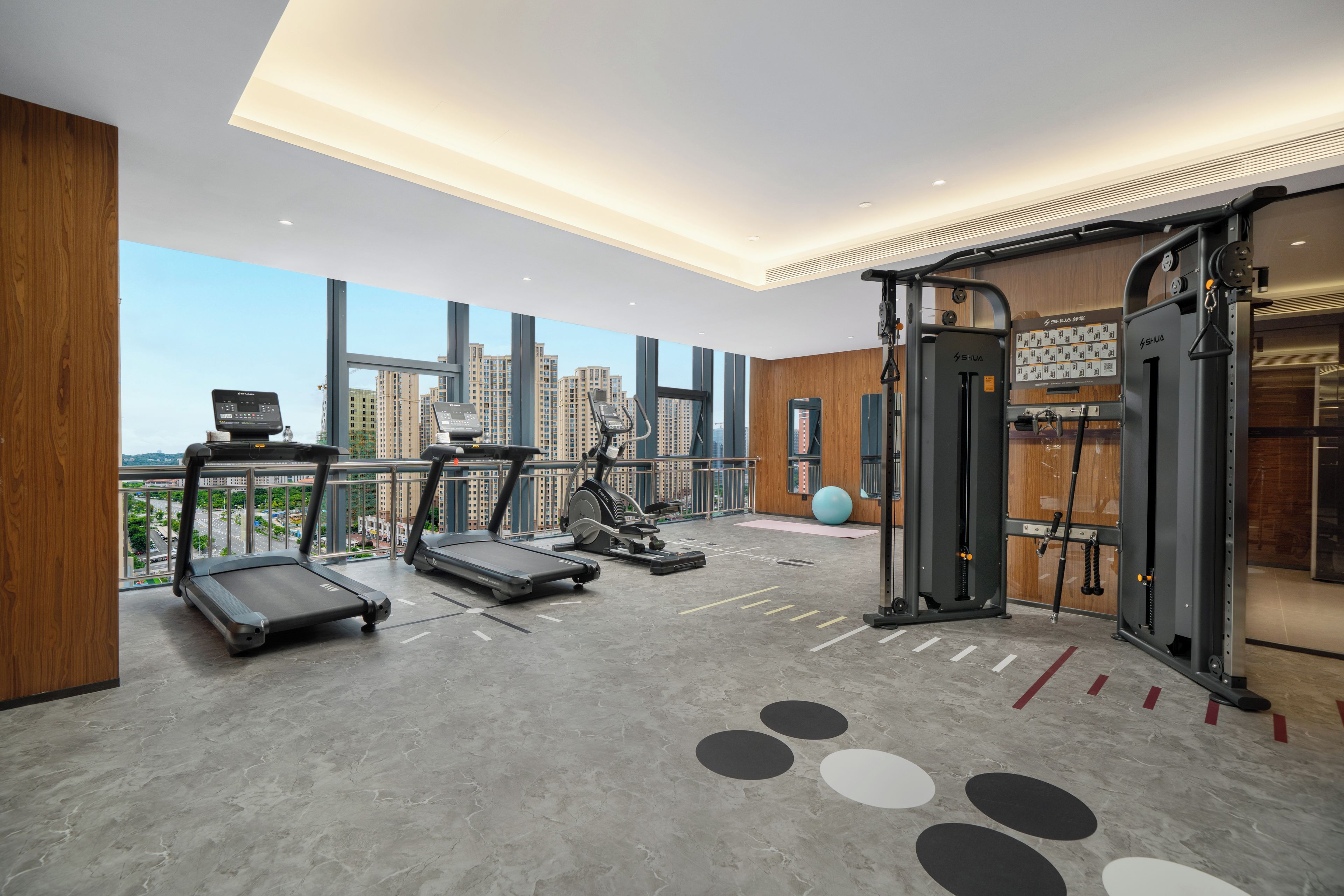 Un gimnasio con cintas de correr, elípticas y equipo de levantamiento de pesas.