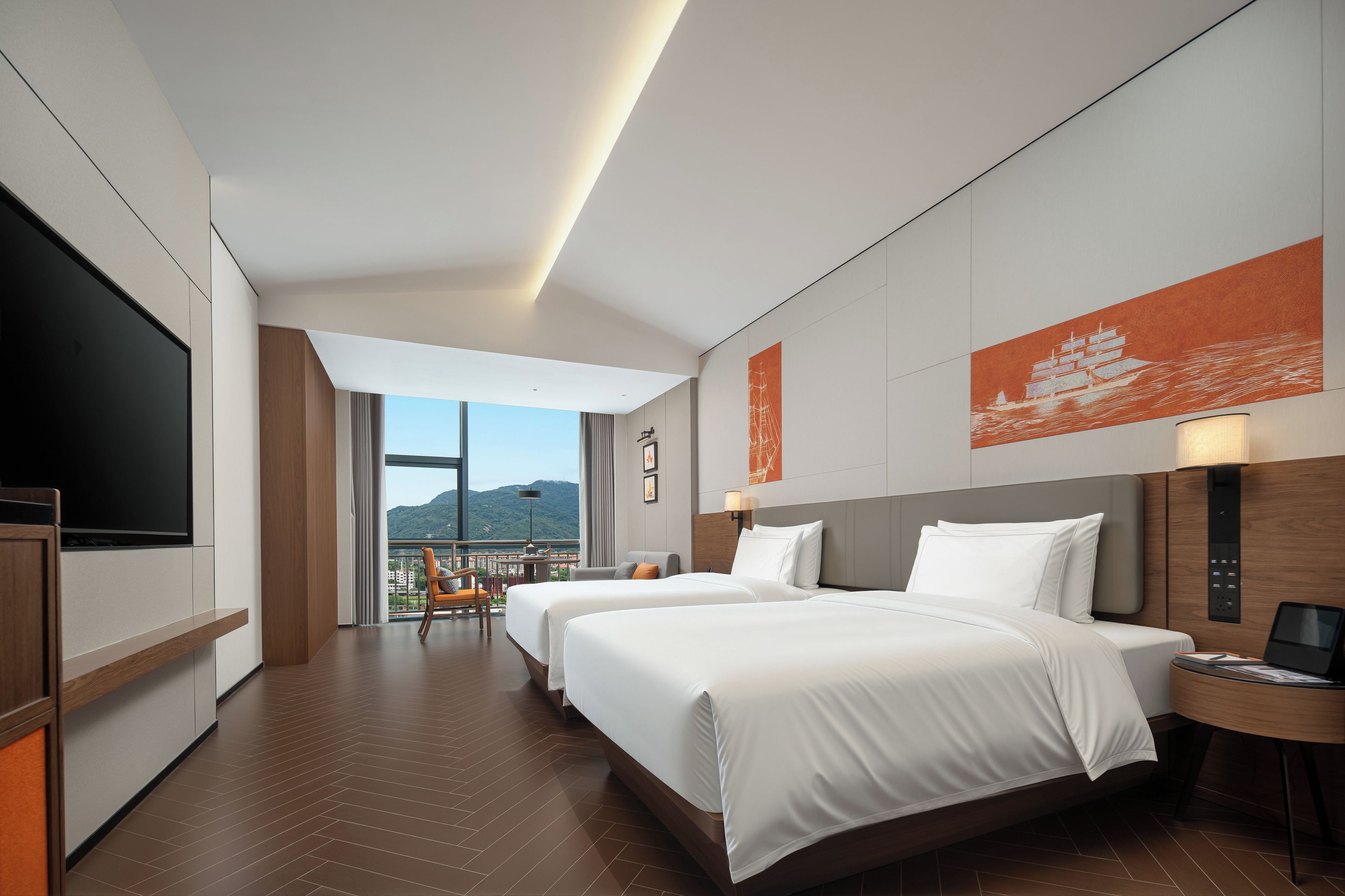 A hotel room with two beds, a TV, a desk, and a view of the mountains.