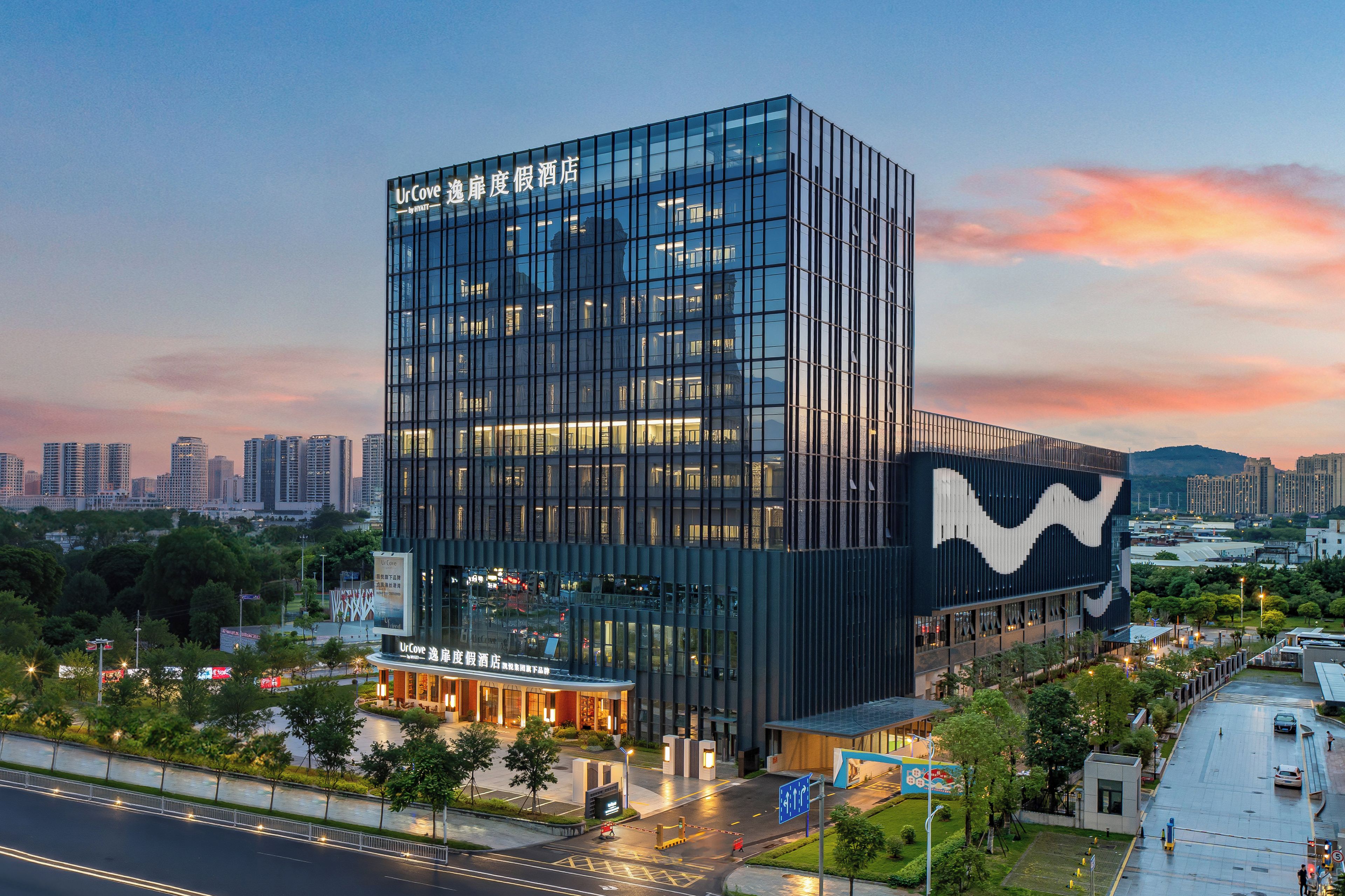 A modern hotel with a glass facade and a distinctive wave pattern on the side.