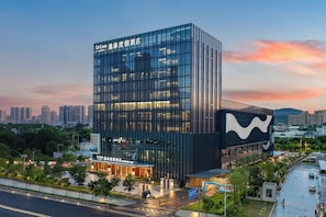 A modern hotel with a glass facade and a distinctive wave pattern on the side. - UrCove by Hyatt Quanzhou Urban  (Quanzhou)