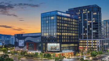 A modern hotel with a glass facade, multiple floors, and a well-lit entrance.