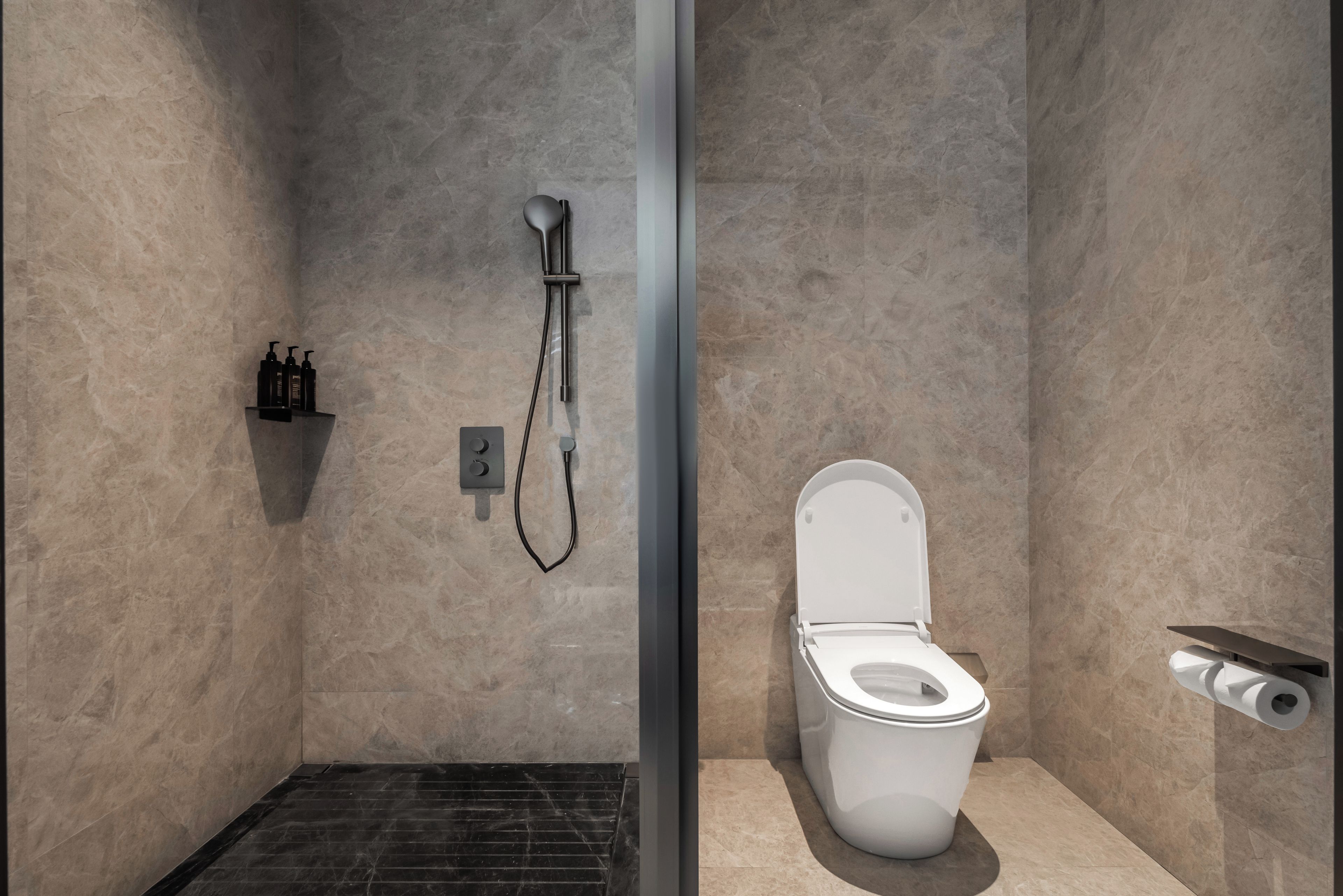 A bathroom with a shower, toilet, and a shelf with toiletries.