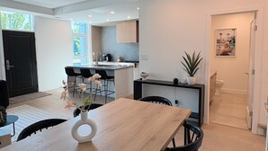 A modern kitchen with a dining area, a black chair, and a vase with flowers. - 3-bedroom townhome with roof top patio - Gyro Beach across the street (Kelowna)