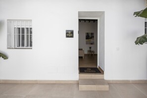 Una entrada limpia y moderna con puerta de cristal, un escalón y un cartel con el nombre del establecimiento.