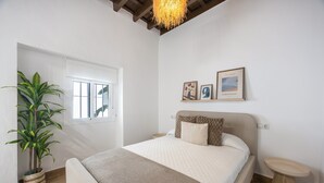 Ein Schlafzimmer mit einem Bett, einem Nachttisch, einer Topfpflanze und einem Fenster.