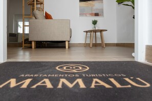 Ein Hotel Eingang mit Fußmatte, auf der 'Apartamentos Turísticos Mamalu' steht.