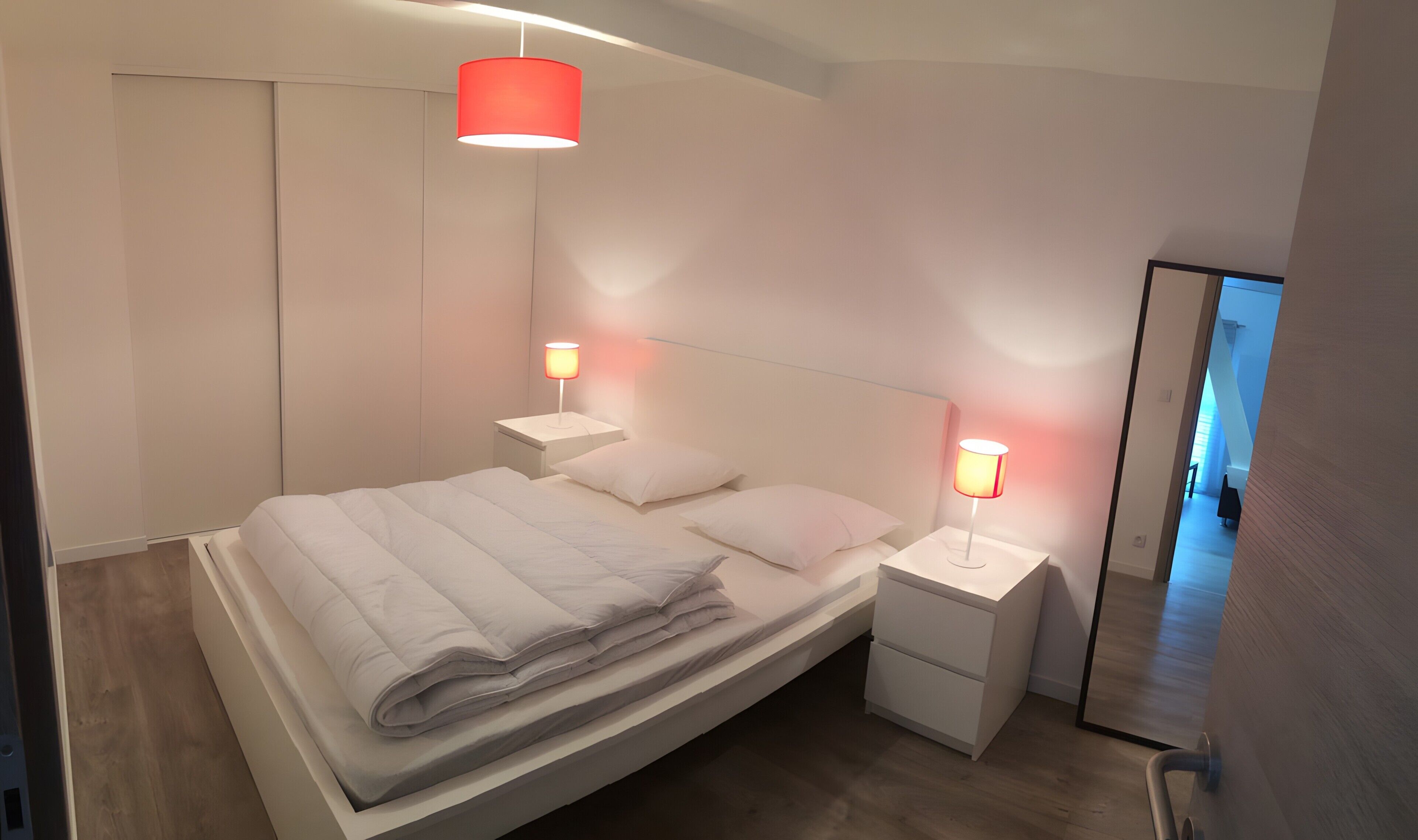 Ein modernes Schlafzimmer mit einem Bett, Nachttischen und einem Spiegel.