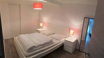 Ein modernes Schlafzimmer mit einem Bett, Nachttischen und einem Spiegel.