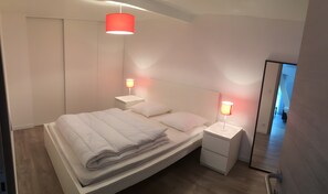 A modern bedroom with a bed, bedside tables, and a mirror.
