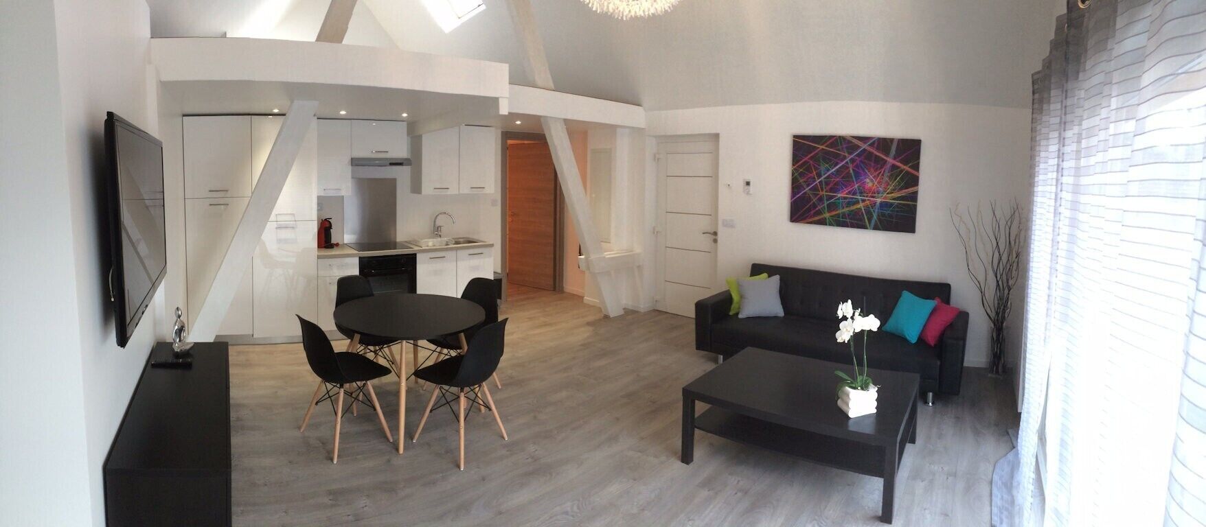 Een moderne woonkamer met een eethoek, een zwarte bank en een salontafel.