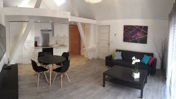 Een moderne woonkamer met een eethoek, een zwarte bank en een salontafel.