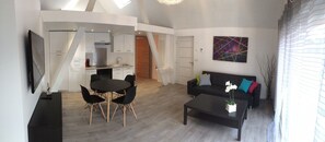A modern living room with a dining area, a black sofa, and a coffee table.