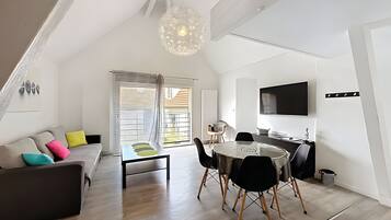 Een moderne woonruimte met een slaapkamer op entresol, een eethoek en een keuken.