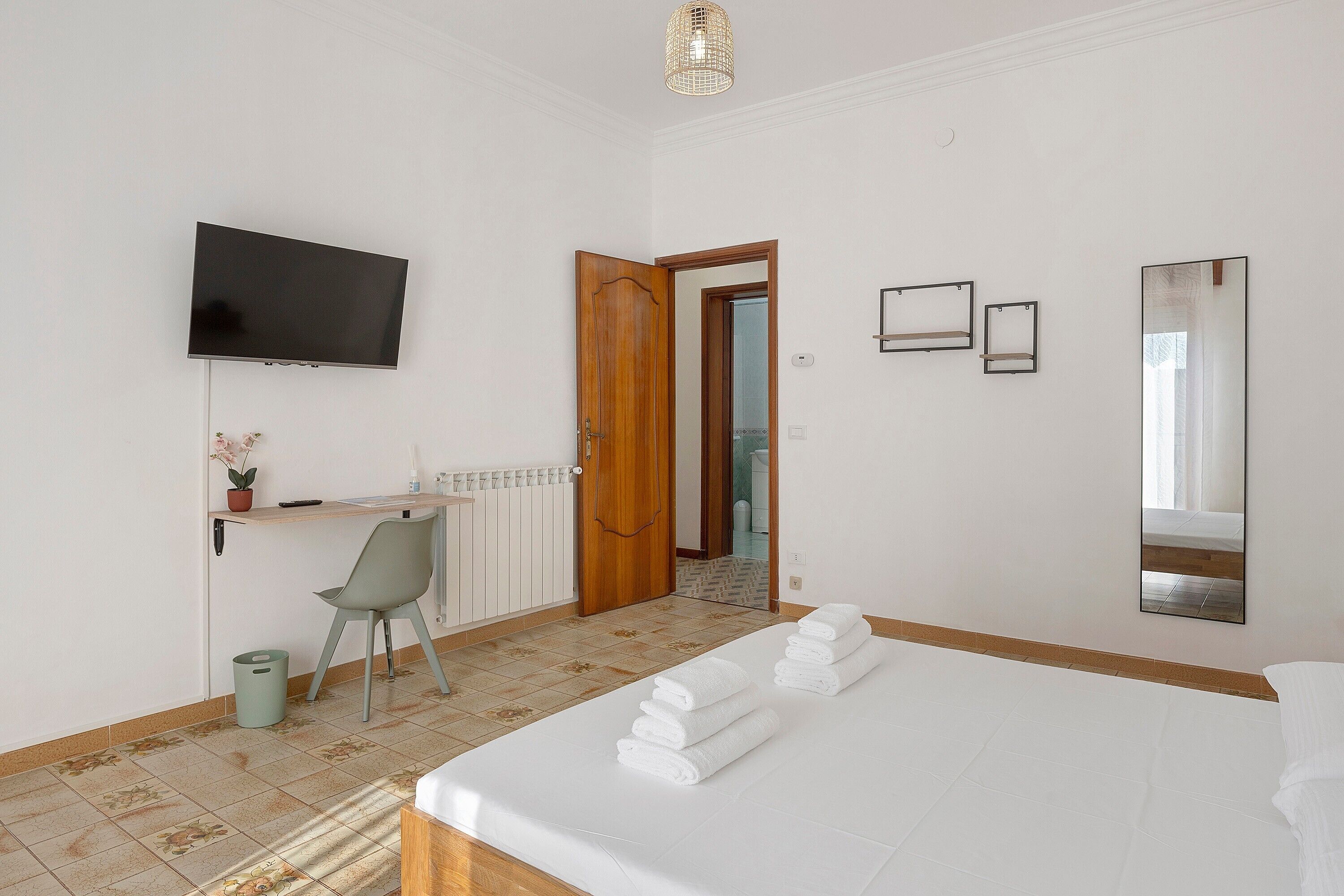Ein Hotelzimmer mit Bett, Schreibtisch, Stuhl, Fernseher und einem durchgegangene Tür sichtbaren Badezimmer.
