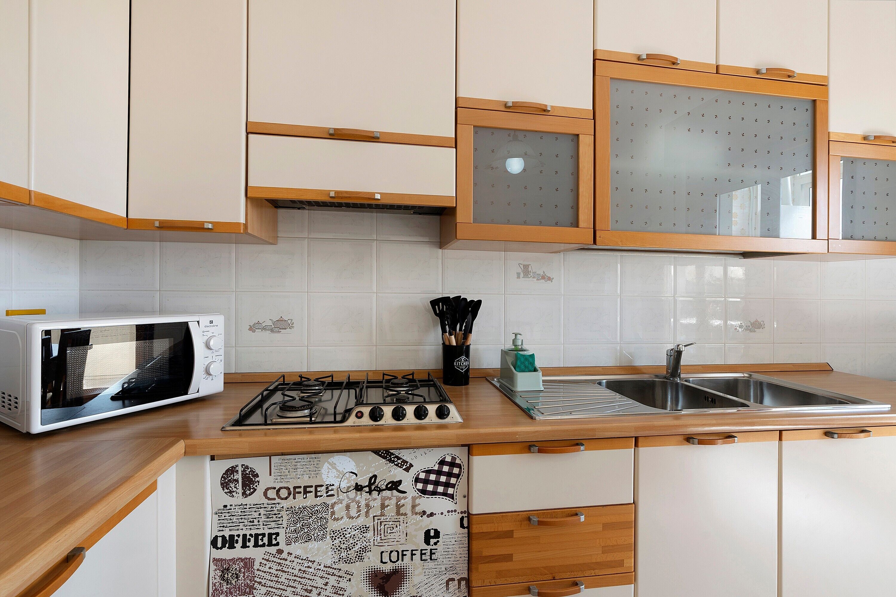 A kitchen with white cabinets, a microwave, a gas stove, and a sink.