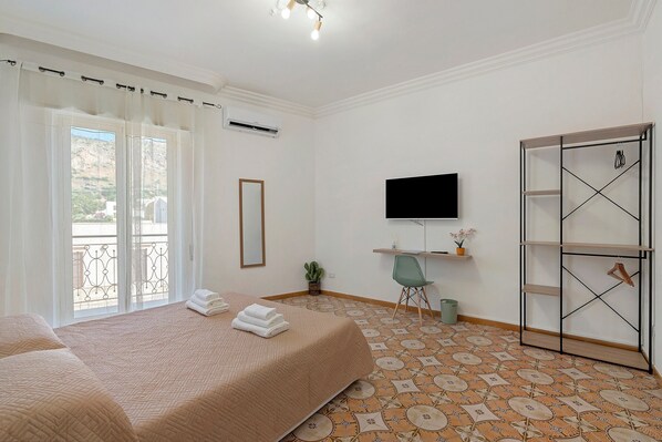 A hotel room with a bed, a TV, a wardrobe, and a balcony with a view.