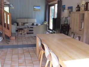 A living room with a sofa, a wooden dining table, and chairs. - Between the Sea and Nature – A Family Home Just Steps from the Beaches in Quiet Plouha (Plouha)