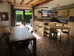 A kitchen with a dining area, a view through a glass door, and a tiled floor. - Between the Sea and Nature – A Family Home Just Steps from the Beaches in Quiet Plouha (Plouha)