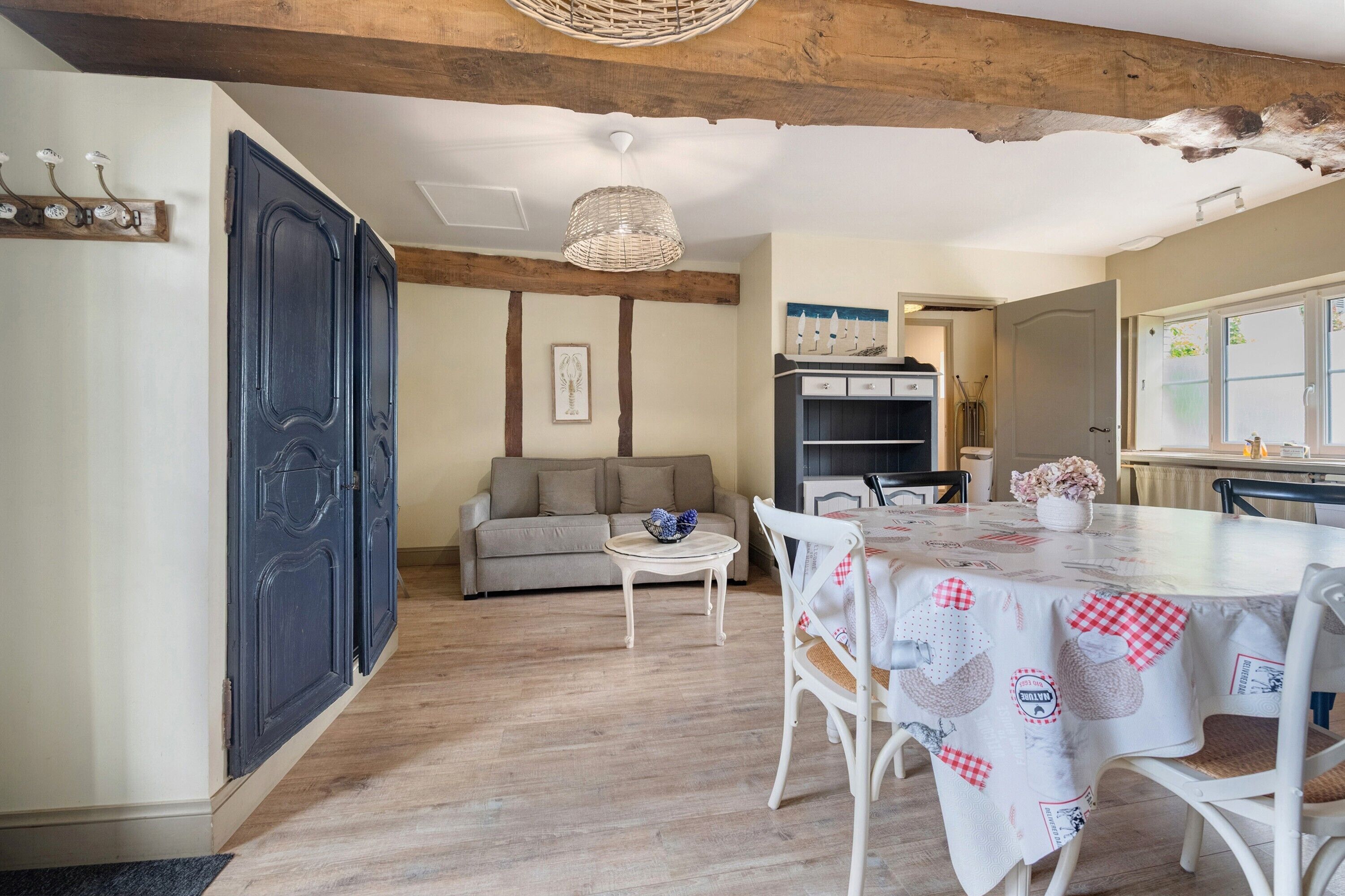 Ein Zimmer mit Esstisch, Stühlen, einer Couch, einem Schrank und einer Decke mit sichtbaren Balken.