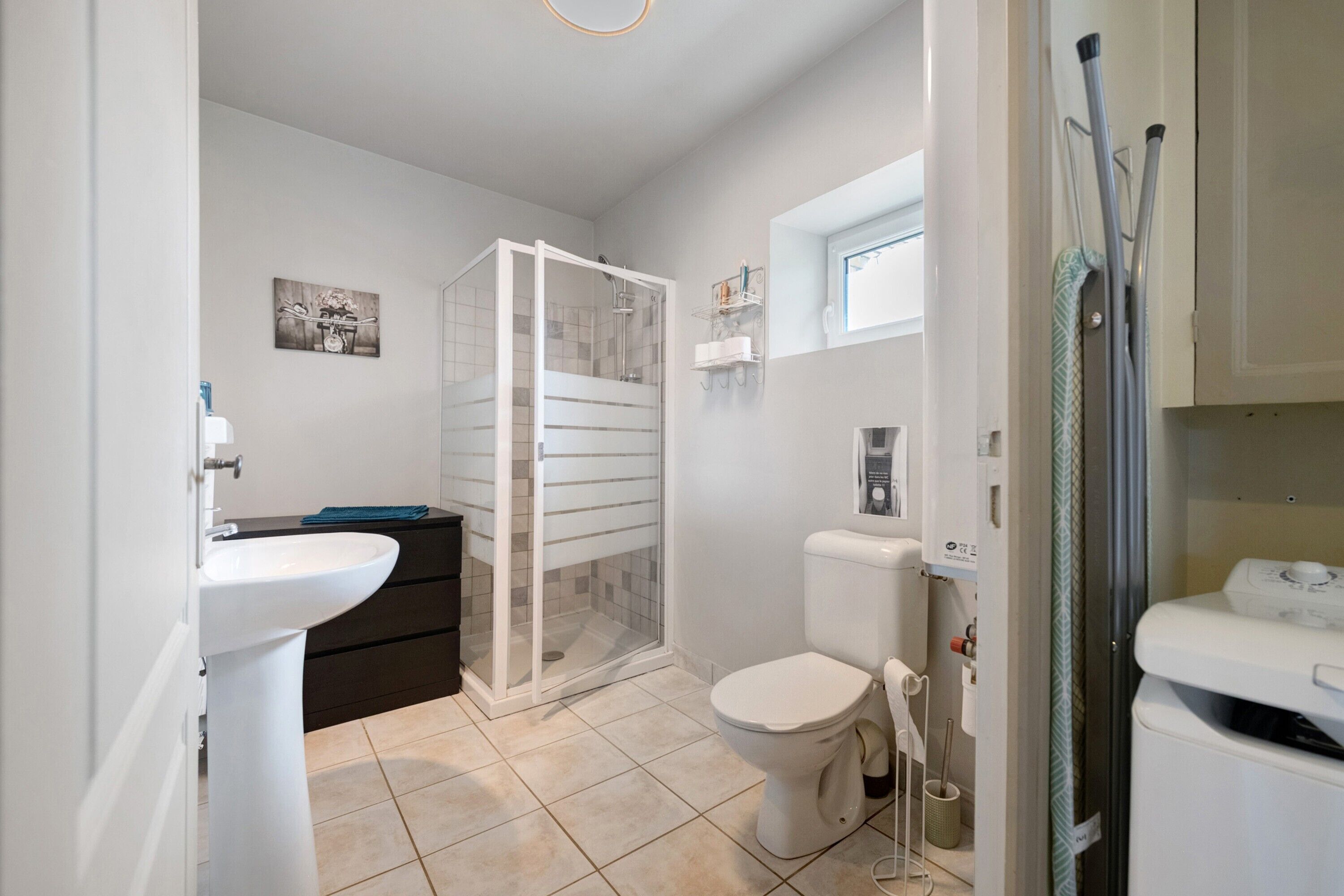 Un bagno completo di doccia, toilette, lavandino e finestra.