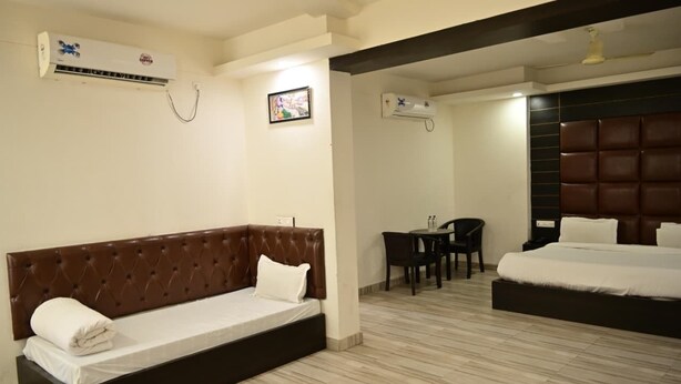 A hotel room with a bed, a sofa, a desk, and two air conditioning units. - SBM Guest House (Salasar)