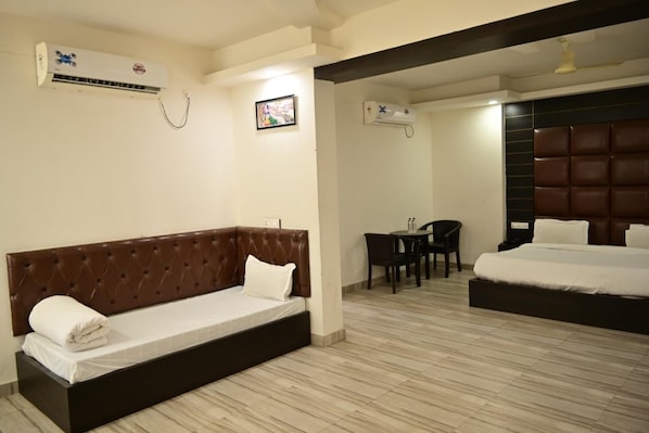 Una habitación de hotel con cama, sofá, escritorio y dos unidades de aire acondicionado.