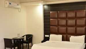 A modern hotel room with a large bed, a small table with chairs, a ceiling fan, and a wall-mounted air conditioning unit. - SBM Guest House (Salasar)