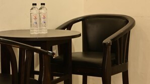 A small round table with two bottles of water and a black chair. - SBM Guest House (Salasar)