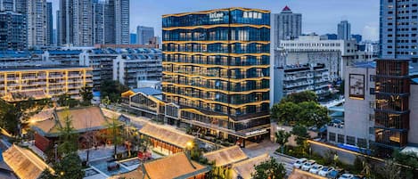 A modern hotel building with multiple floors and a traditional courtyard with tiled roofs.