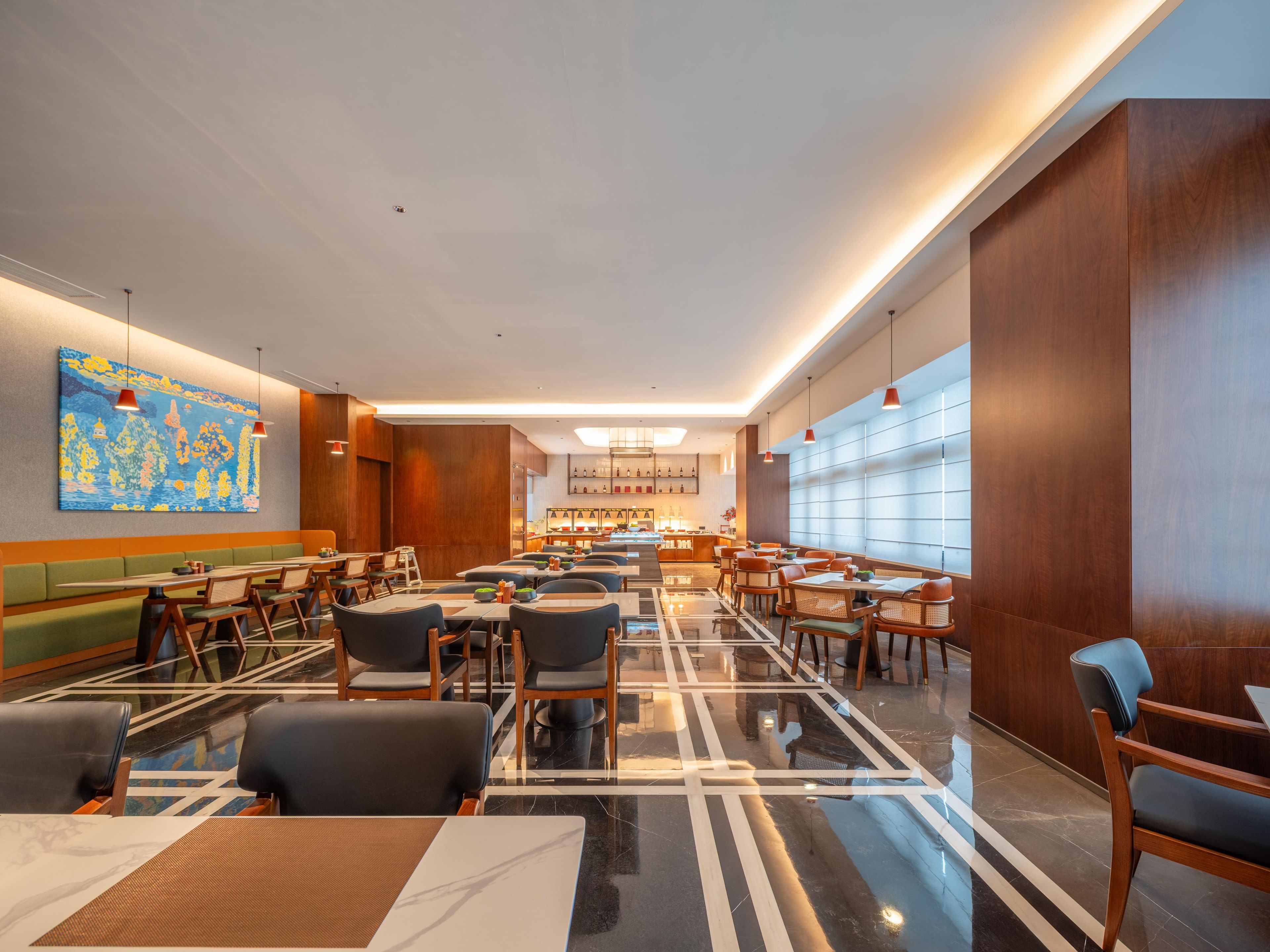A modern hotel lobby with a central bar area, seating arrangements, and a large window providing natural light.