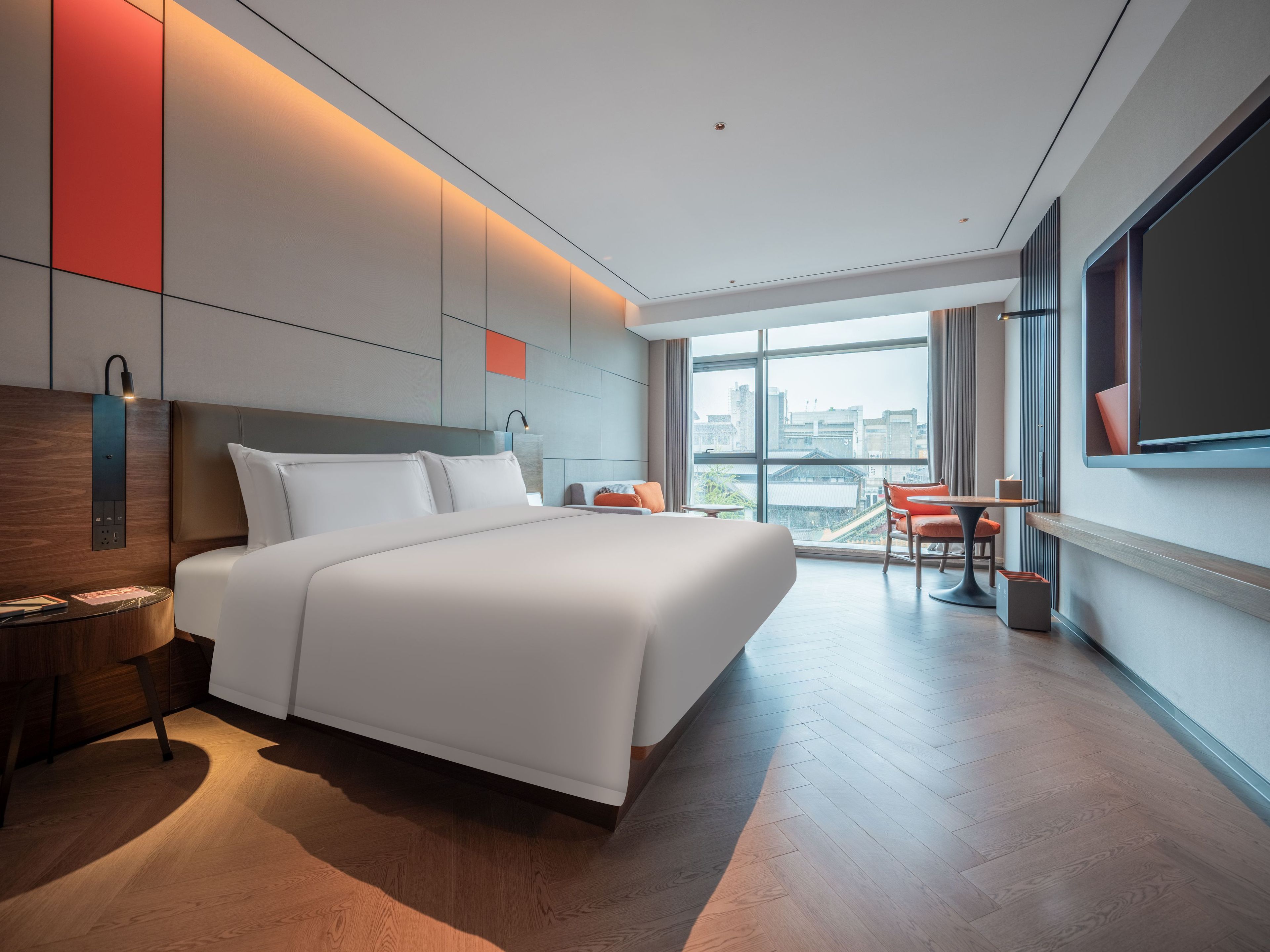 Una habitación de hotel moderna con una cama grande, un escritorio y vistas a la ciudad.