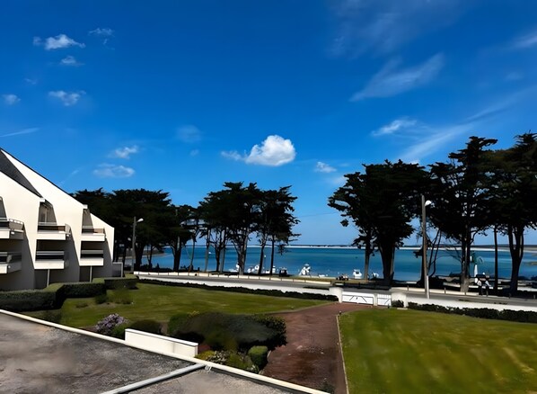 A modern building with a clear view of the sea, surrounded by trees and a well-maintained lawn. - Charming Seafront Apartment in Le Croisic (Le Croisic)