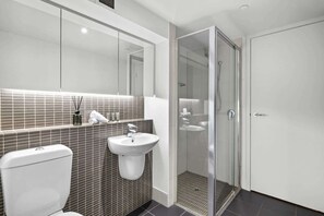 Ein modernes Badezimmer mit Toilette, Waschbecken und Duschkabine aus Glas.