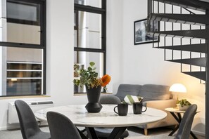 Ein modernes Wohnzimmer mit einem runden Tisch, einer Couch, einem Couchtisch und einer Wendeltreppe.