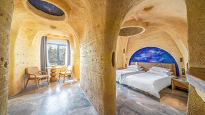 A room with a bed, a table, and chairs, with a large window and a view of the outdoors. - 1168 Starry Sky Astronomy Hotel (Huzhou)