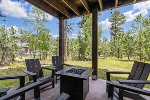 An outdoor patio with Adirondack chairs and a built-in fire pit.