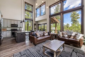 A spacious living area with a large window, a kitchen with modern appliances, and a cozy seating arrangement.