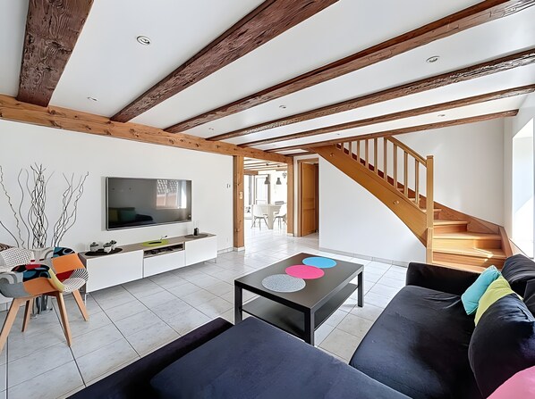 En moderne stue med TV, sofa, sofabord og trappe.