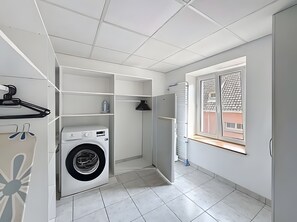 Une buanderie équipée d’un lave-linge, d’étagères et d’une fenêtre.