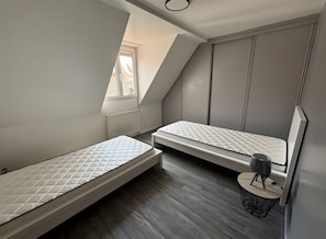 Et lille, moderne loftværelse med to køjesenge, et skydetagvindue og et rundt bord.